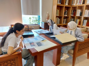 three students viewing magazines in a reading room