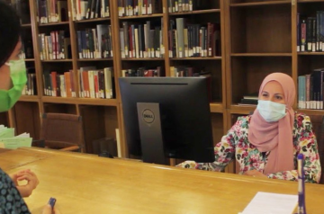Veiled lady sitting on a desk with a computer
