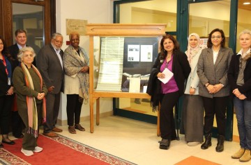 Group of people standing beside a glass window with historic ornaments
