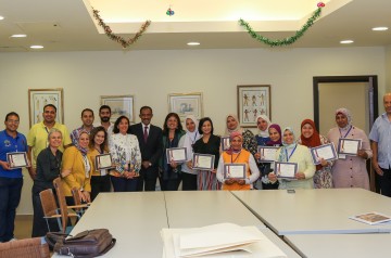 A group of people taking a group photo holding certificates in a classroom